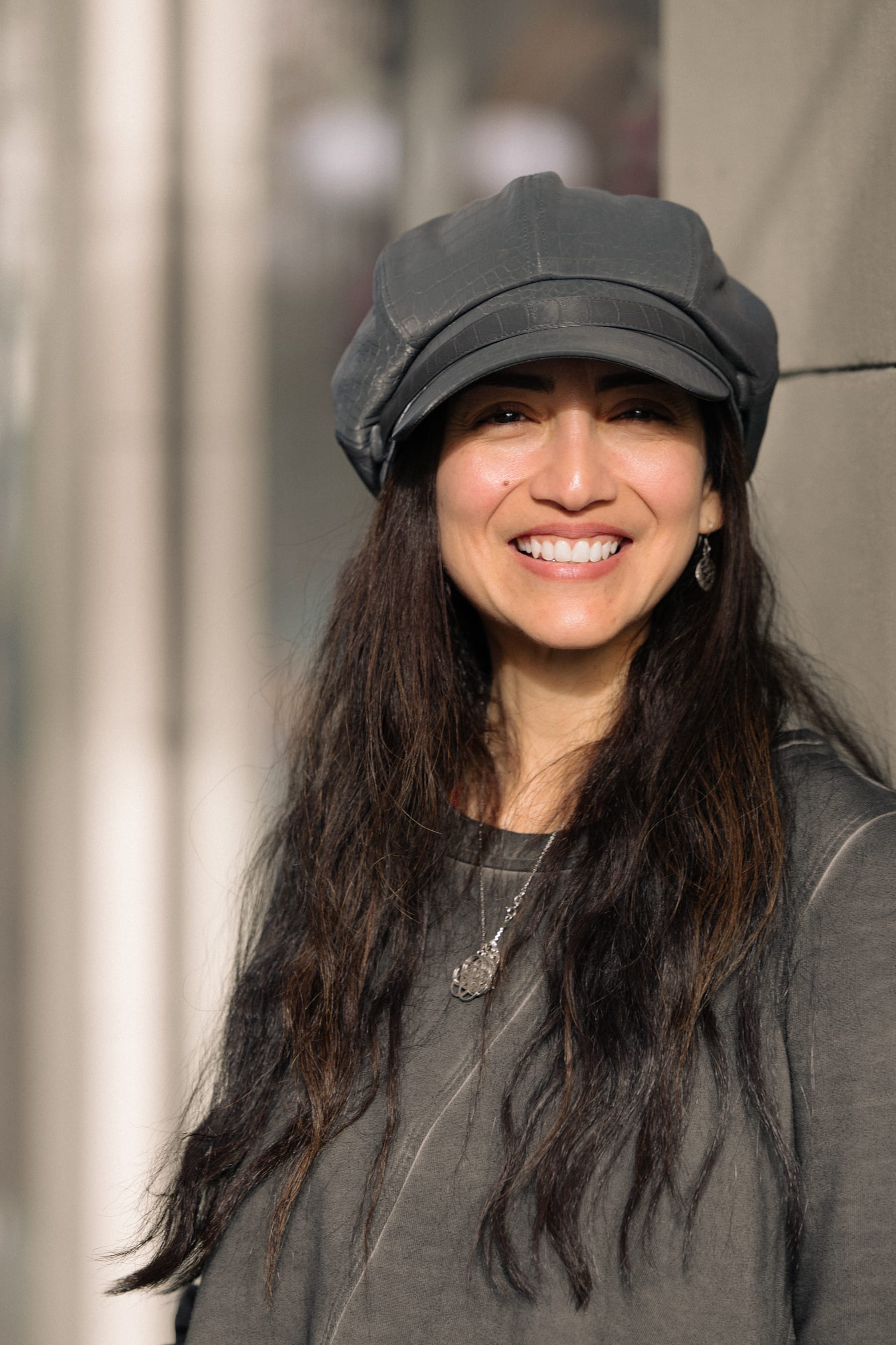 Pamela, owner of Simple Life, smiling in a leather newsboy cap